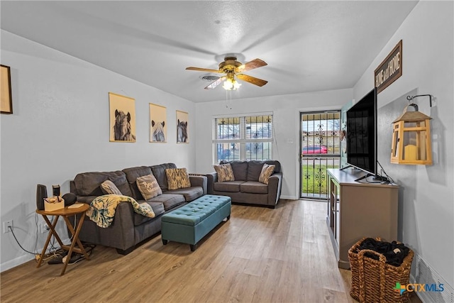 living room with light wood finished floors, baseboards, and a ceiling fan