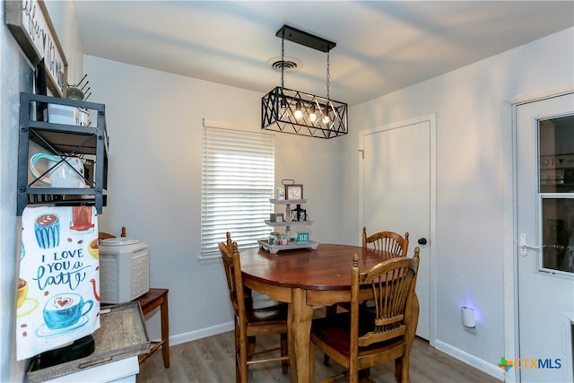 dining space with hardwood / wood-style floors and an inviting chandelier