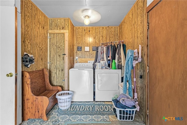 laundry area featuring laundry area, wood walls, and washer and clothes dryer