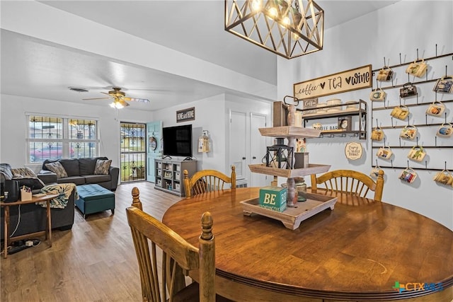 dining space featuring ceiling fan with notable chandelier, wood finished floors, and visible vents