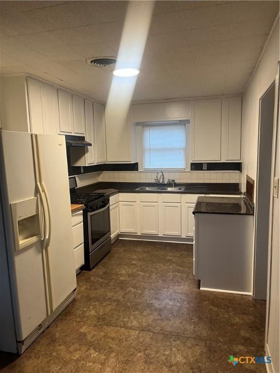 kitchen with sink, backsplash, white fridge with ice dispenser, stainless steel range with gas cooktop, and white cabinets