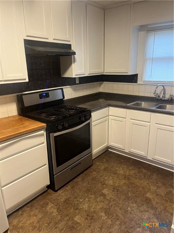 kitchen with sink, stainless steel gas stove, white cabinetry, and tasteful backsplash