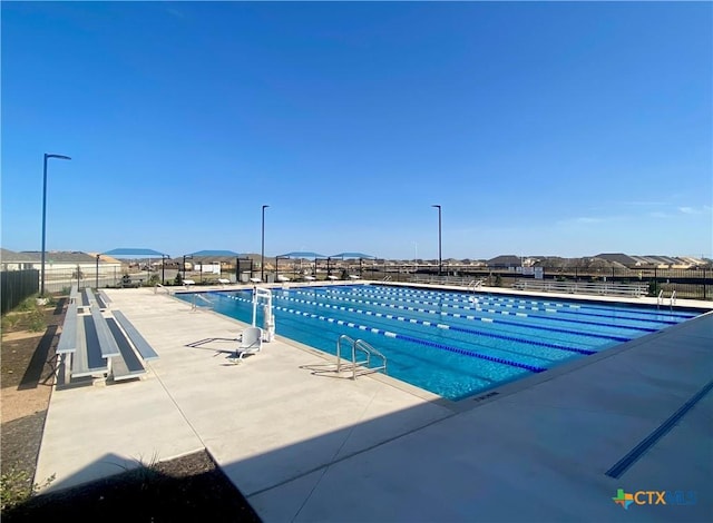 pool with a patio area and fence