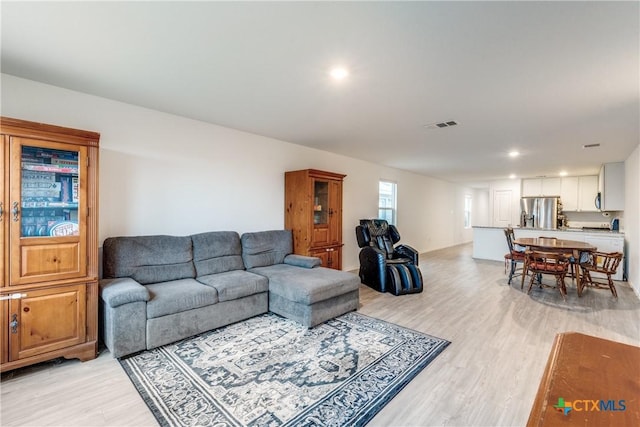 living room with light wood-type flooring, visible vents, and recessed lighting