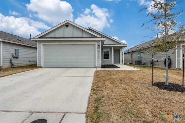 ranch-style home featuring central AC unit, board and batten siding, a garage, driveway, and a front lawn