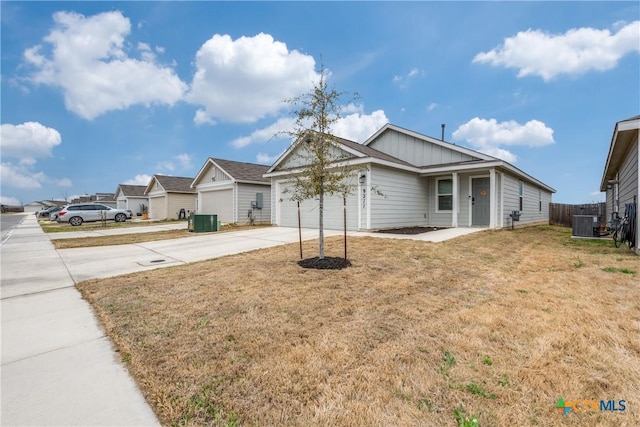 ranch-style house with concrete driveway, central air condition unit, an attached garage, and a front yard