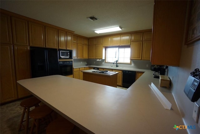 kitchen with sink, a breakfast bar, kitchen peninsula, and black appliances