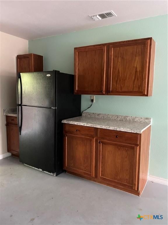 414 Henk Ln, San Marcos, TX 78666 - kitchen featuring brown cabinetry, visible vents, light countertops, and freestanding refrigerator