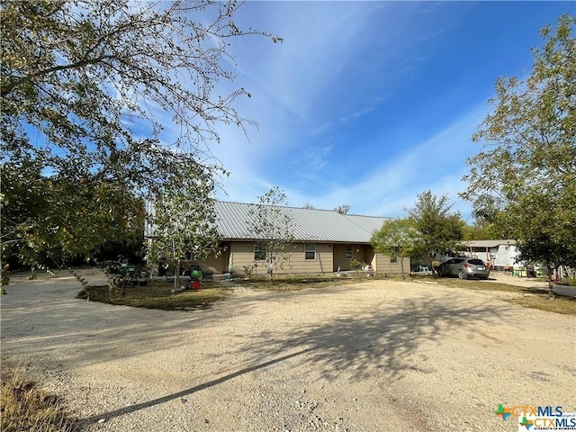 view of front facade featuring dirt driveway and metal roof