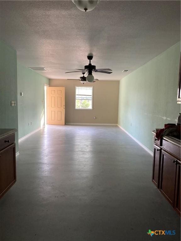 414 Henk Ln, San Marcos, TX 78666 - unfurnished living room featuring a textured ceiling, ceiling fan, baseboards, and finished concrete floors