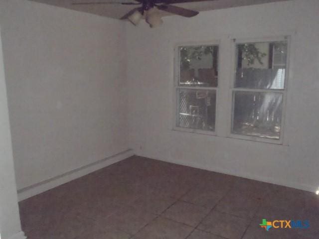 empty room featuring baseboards, a ceiling fan, and tile patterned flooring
