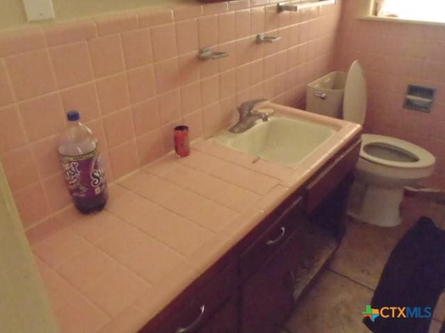 bathroom featuring vanity, toilet, tile patterned flooring, and tile walls