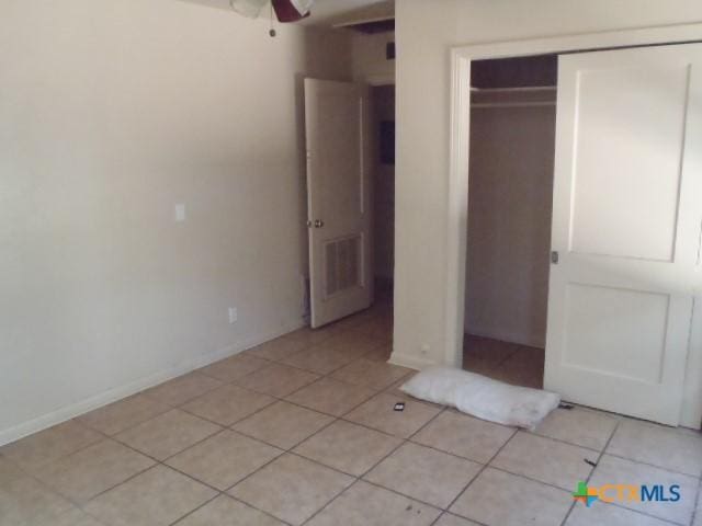 unfurnished bedroom featuring light tile patterned flooring, visible vents, baseboards, and a closet