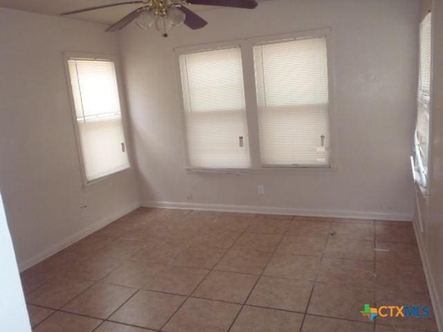 unfurnished room with light tile patterned floors, ceiling fan, and baseboards