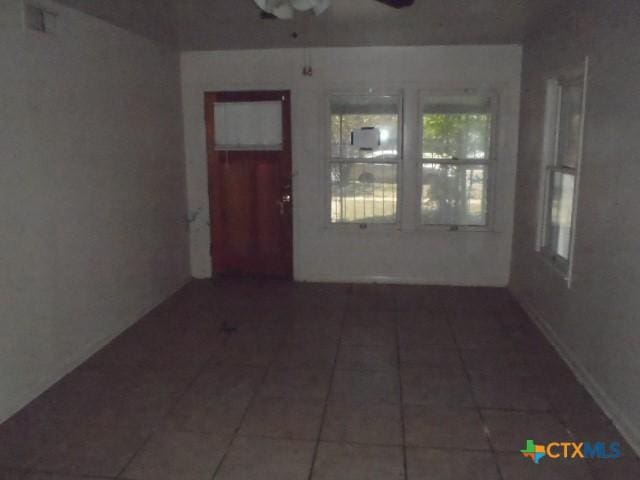 tiled spare room with ceiling fan