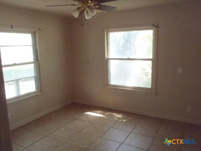 spare room with light tile patterned flooring, ceiling fan, and baseboards