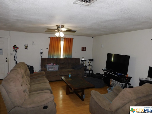 living room with ceiling fan, a textured ceiling, and light hardwood / wood-style flooring