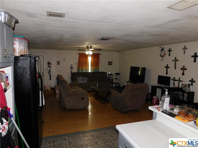 living room with dark wood-type flooring, a textured ceiling, and ceiling fan