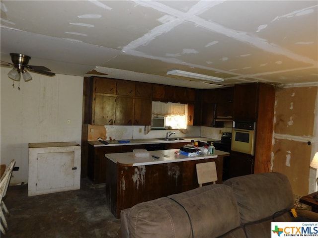 kitchen with stainless steel appliances, a center island, dark brown cabinetry, sink, and ceiling fan