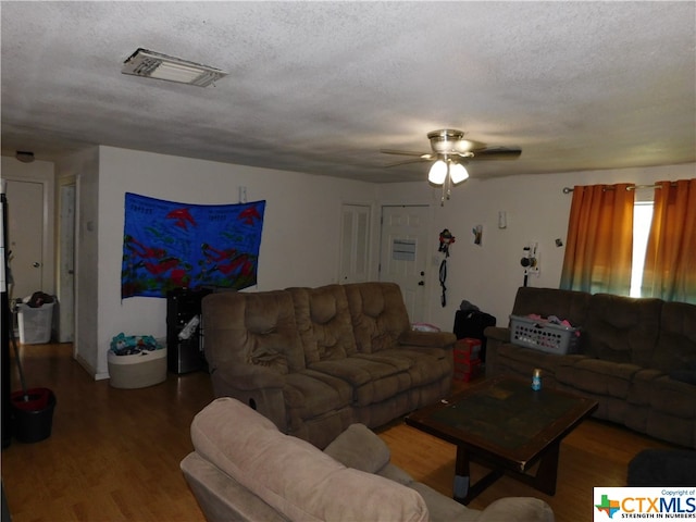 living room with a textured ceiling, hardwood / wood-style flooring, and ceiling fan