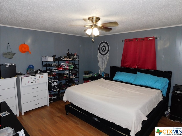 bedroom featuring hardwood / wood-style flooring, ceiling fan, a textured ceiling, and ornamental molding