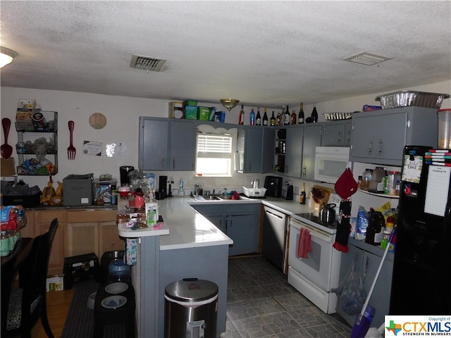 kitchen featuring kitchen peninsula, white appliances, and a textured ceiling