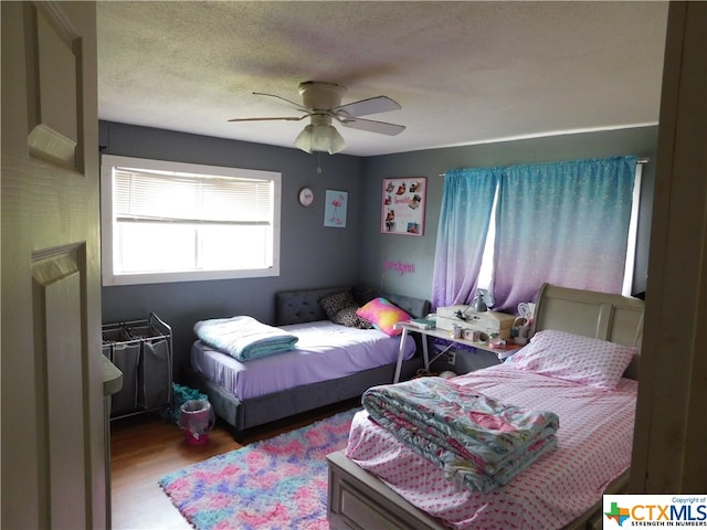 bedroom featuring hardwood / wood-style flooring, ceiling fan, and a textured ceiling