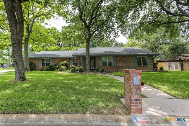 ranch-style home with a front yard and brick siding