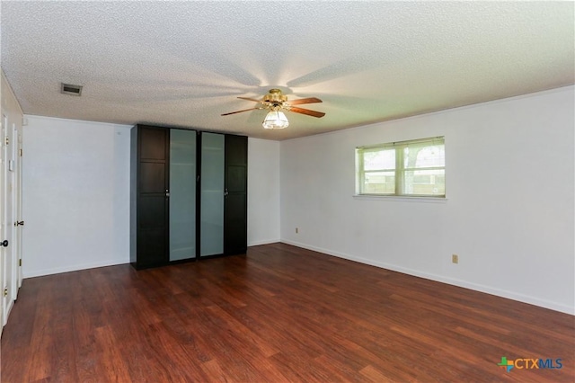 unfurnished bedroom with dark wood-style flooring, a textured ceiling, baseboards, and ceiling fan