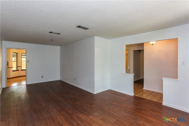 spare room with wood finished floors, a textured ceiling, and baseboards