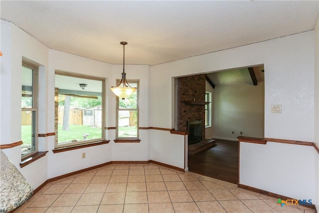 spare room featuring light tile patterned floors, baseboards, and a brick fireplace