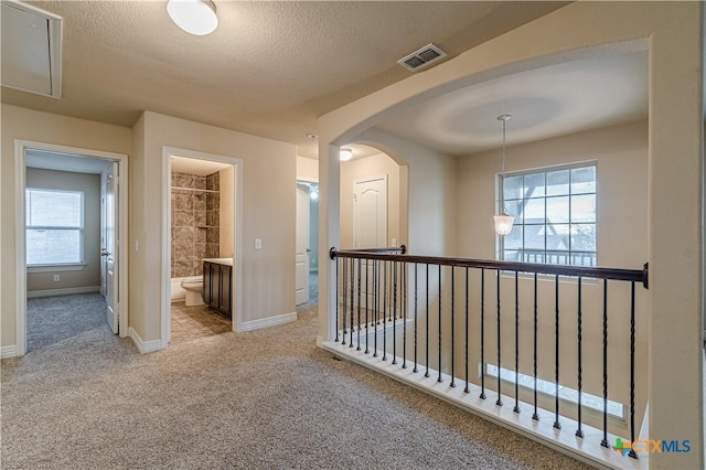 corridor featuring light colored carpet and a textured ceiling