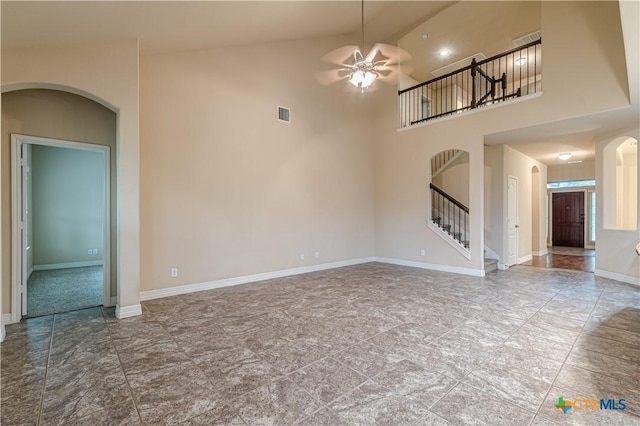 unfurnished living room with ceiling fan and a high ceiling