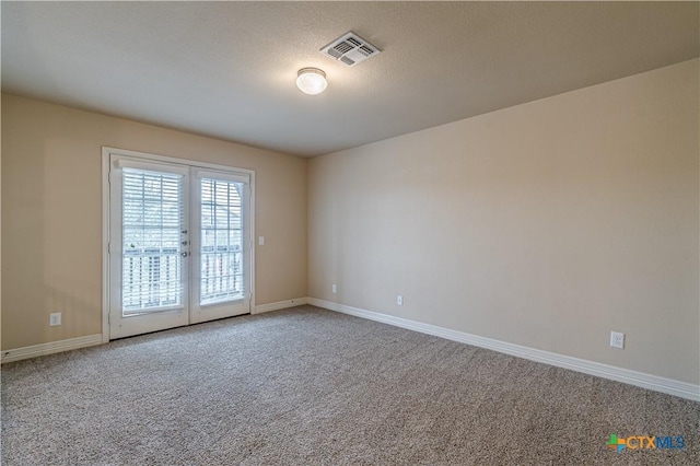 carpeted empty room featuring a textured ceiling and french doors