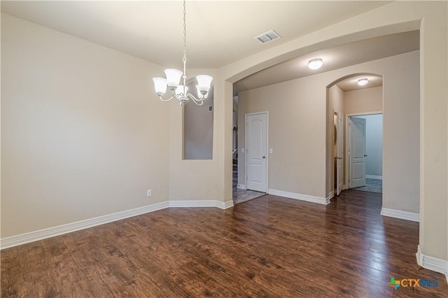 empty room with dark hardwood / wood-style floors and a notable chandelier