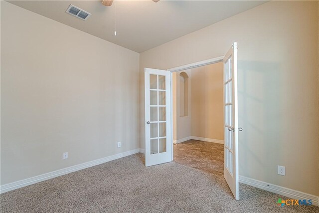 unfurnished room featuring light carpet, ceiling fan, and french doors