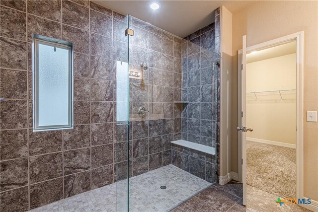 bathroom with tile patterned flooring and a tile shower