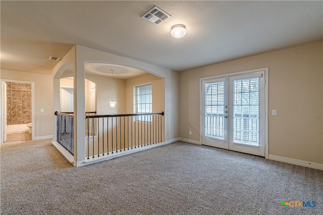 carpeted empty room featuring french doors and a textured ceiling