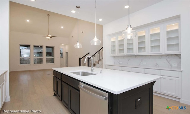 kitchen featuring white cabinetry, sink, a kitchen island with sink, stainless steel dishwasher, and decorative backsplash