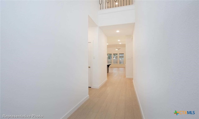 hall with light hardwood / wood-style floors and a high ceiling