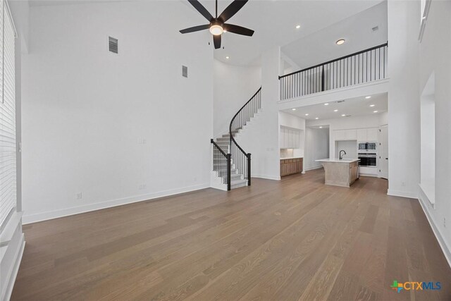 living room featuring hardwood / wood-style flooring, ceiling fan, and high vaulted ceiling