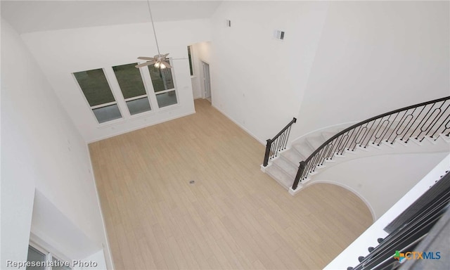 stairs with hardwood / wood-style flooring, ceiling fan, and a towering ceiling