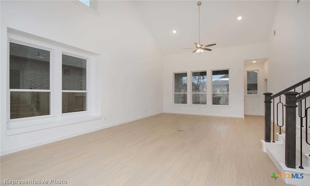 unfurnished living room with ceiling fan, plenty of natural light, high vaulted ceiling, and light wood-type flooring