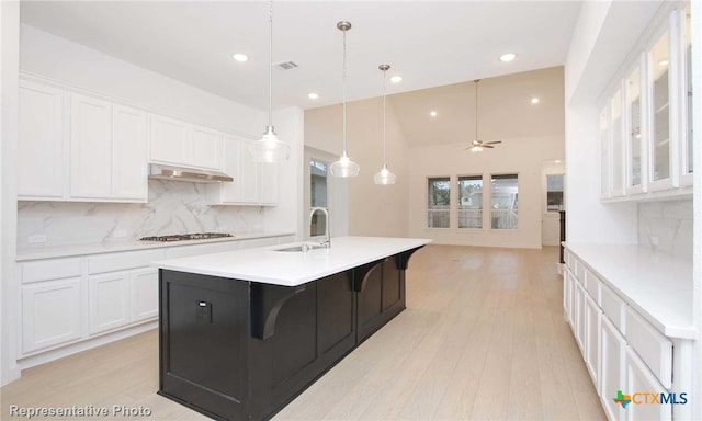 kitchen featuring tasteful backsplash, white cabinetry, sink, and ceiling fan