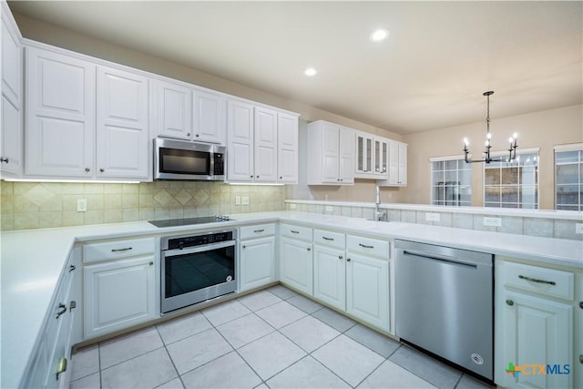 kitchen featuring appliances with stainless steel finishes, decorative light fixtures, sink, white cabinets, and backsplash