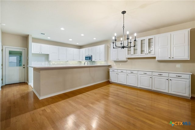 kitchen featuring white cabinetry, decorative light fixtures, a chandelier, and light wood-type flooring