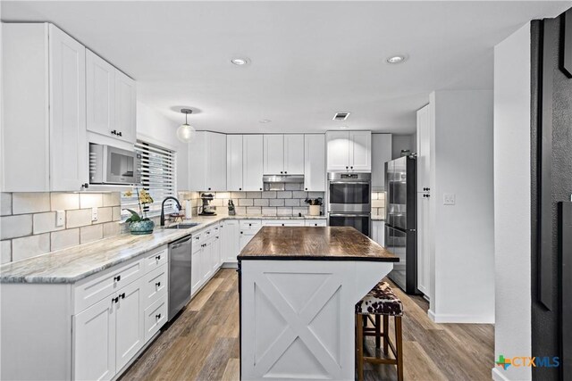 701 W Esparada Dr, Georgetown, TX 78628 - kitchen featuring stainless steel appliances, light wood finished floors, backsplash, white cabinets, and recessed lighting