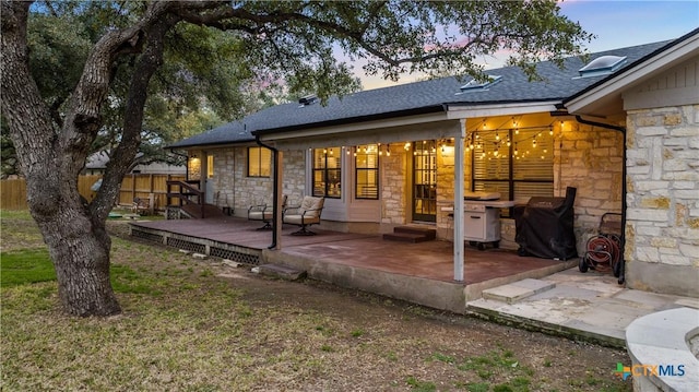 701 W Esparada Dr, Georgetown, TX 78628 - rear view of house featuring stone siding, fence, a shingled roof, a deck, and a patio area