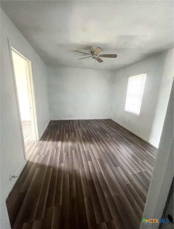 empty room with baseboards, a ceiling fan, and dark wood-style flooring