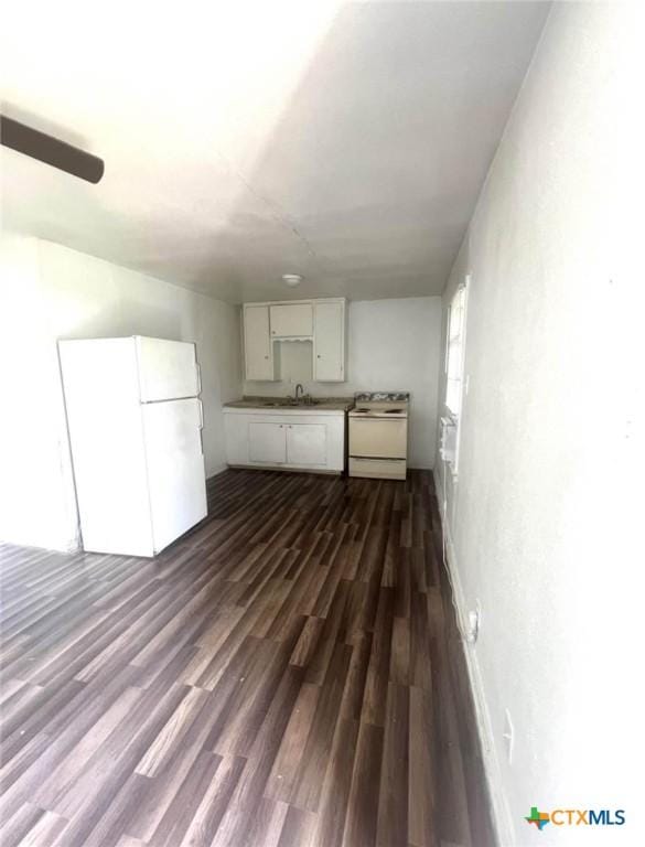 basement with dark wood finished floors, freestanding refrigerator, and a sink